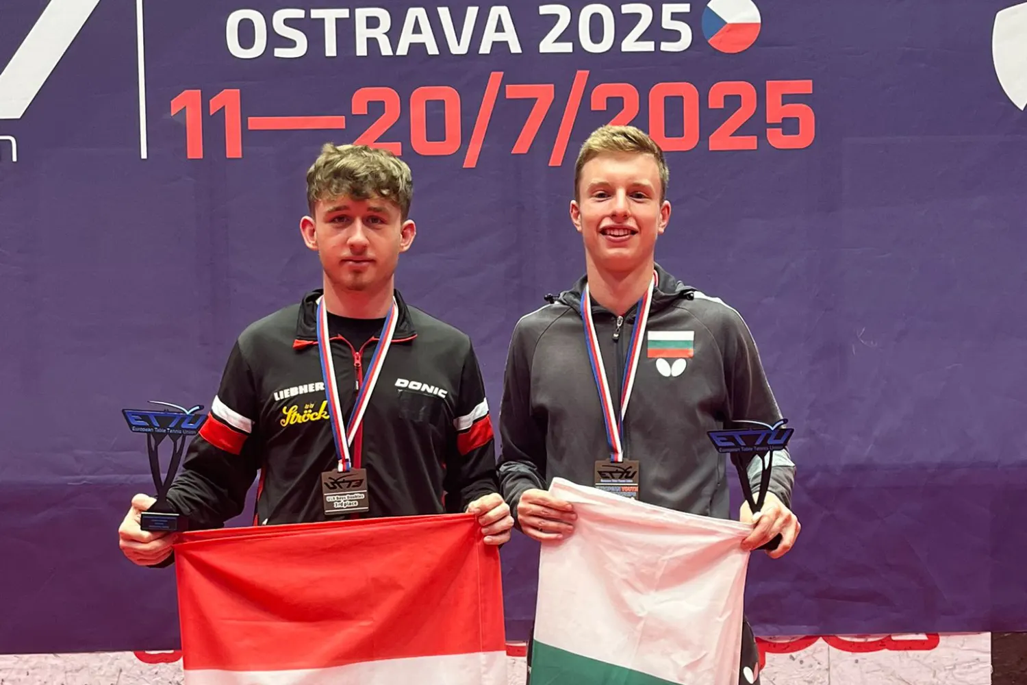 Julian Rzihauschek und sein Team-Partner im Doppel halten die Flaggen ihrer Heimatländer und den Pokal für den dritten Rang in ihren Händen.