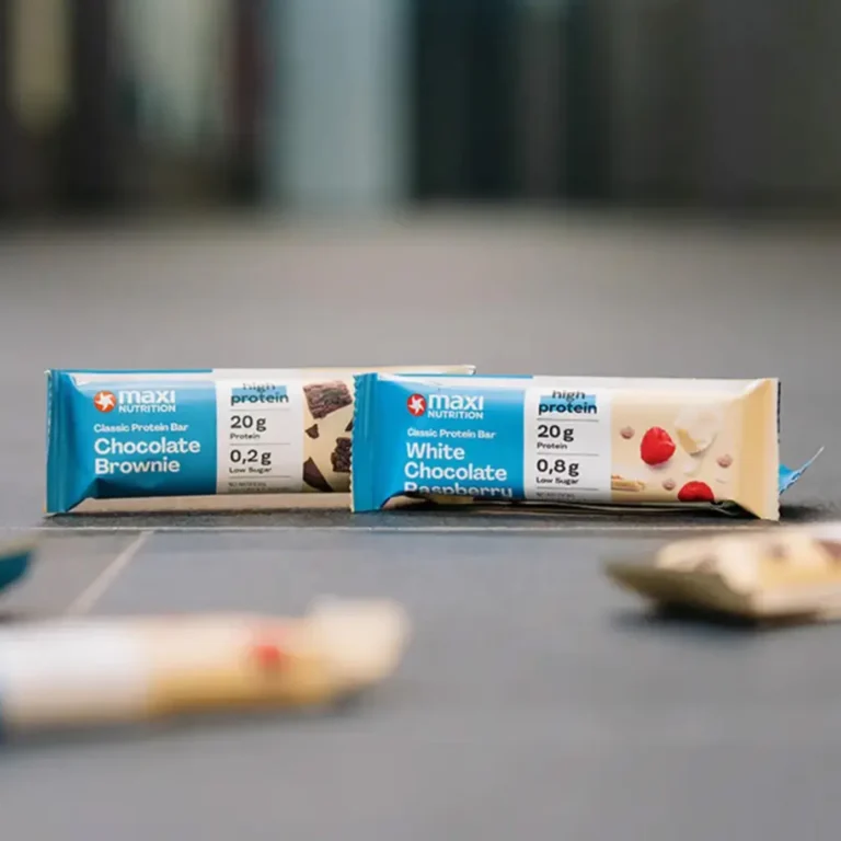 Zwei MaxiNutrition Classic Protein-Bars – Chocolate Brownie und White Chocolate Raspberry – mit 20g Protein und Low Sugar auf grauem Untergrund