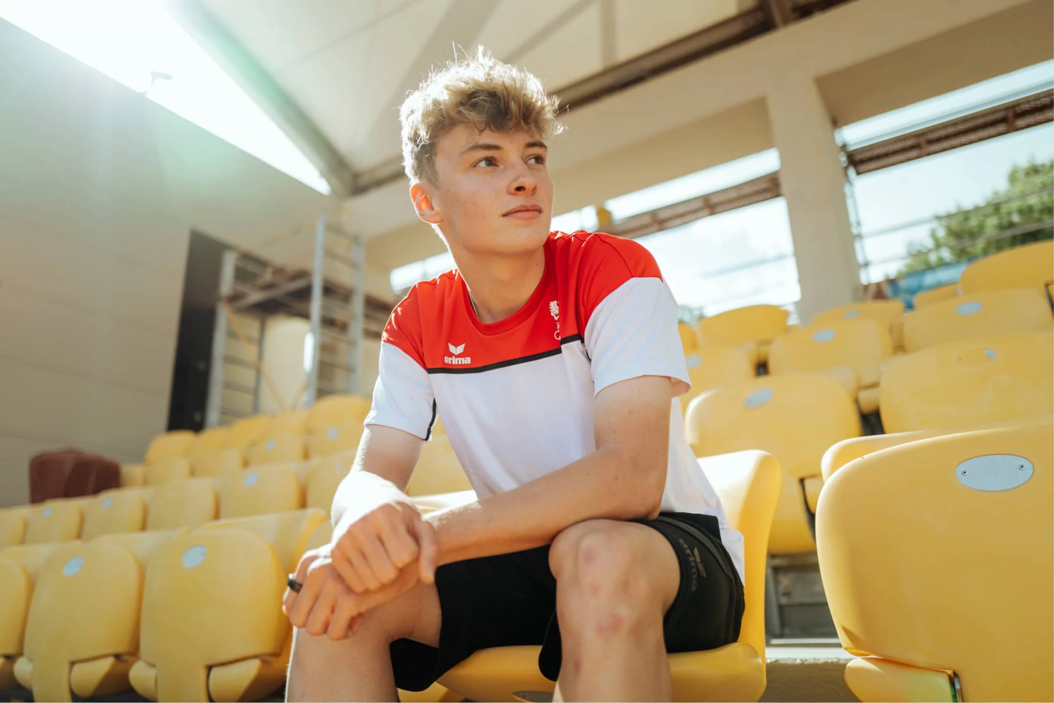 Raphael Okas im Erima-Trikot sitzt nachdenklich auf der Stadiontribüne